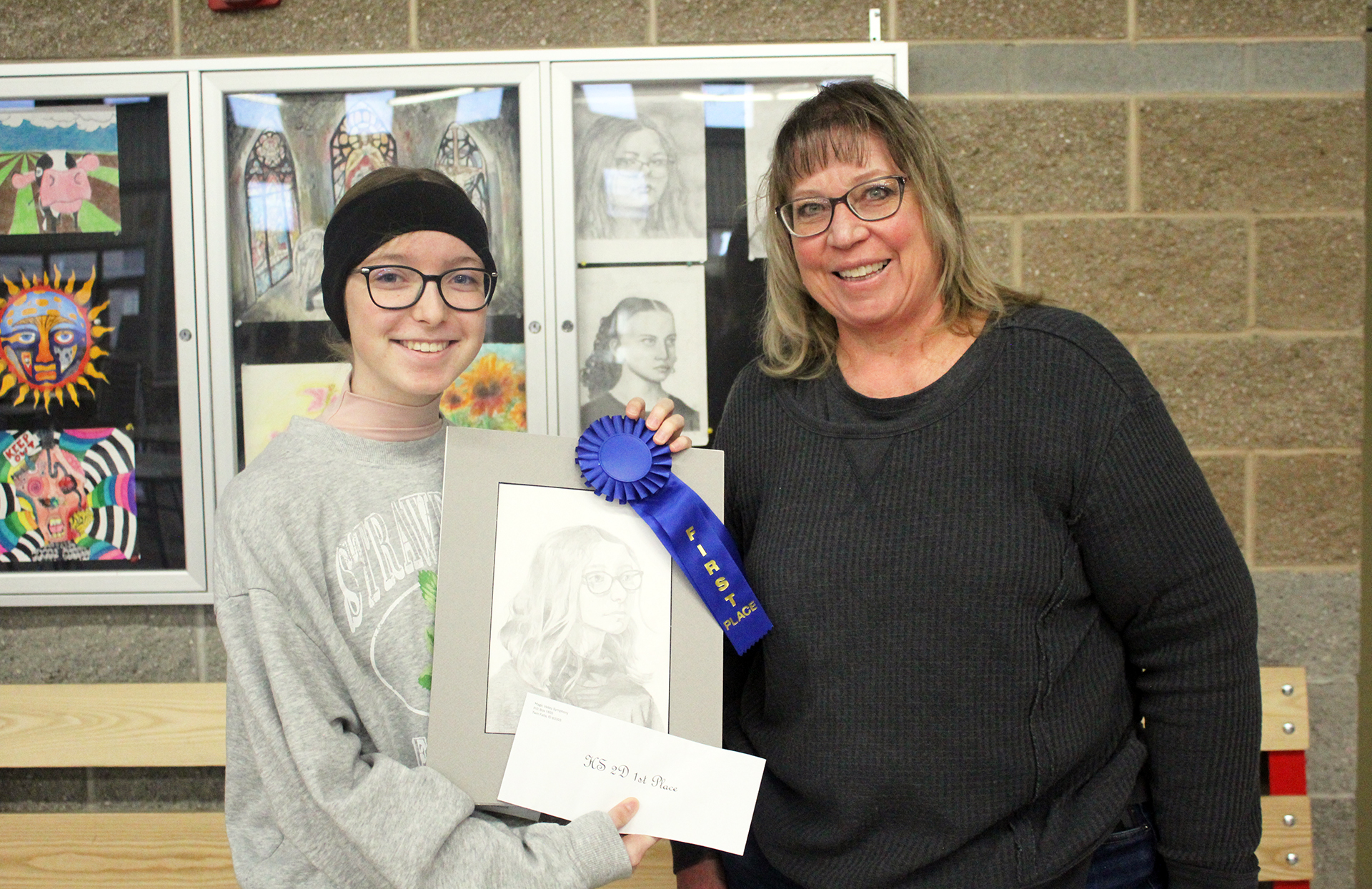 Sophie Paulsen (left) and Ms. Tami Aufderheide pose with Sophie's first place drawing, ribbon, and prize on Monday, Feb. 24. | Photo by Hayley Daniels